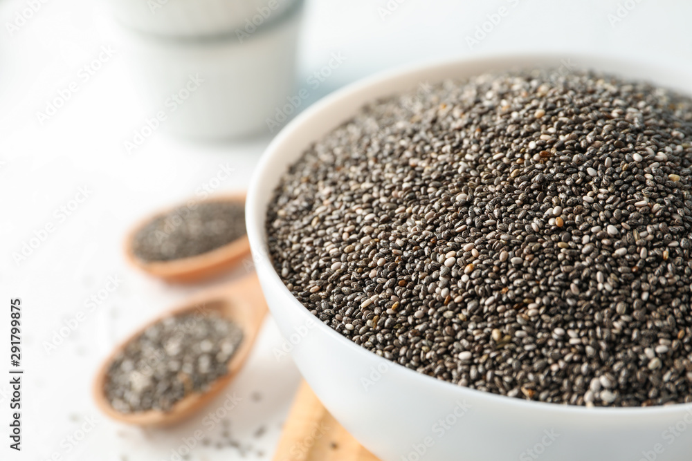 Bowl and spoons with chia on white background, close up