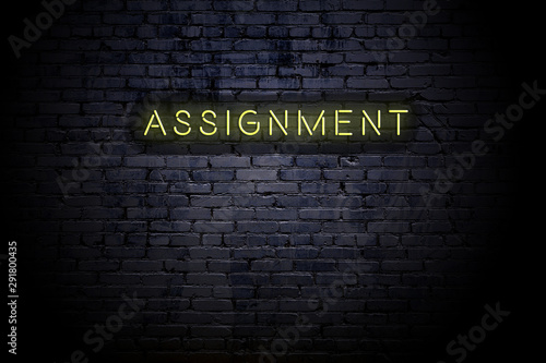 Highlighted brick wall with neon inscription assignment