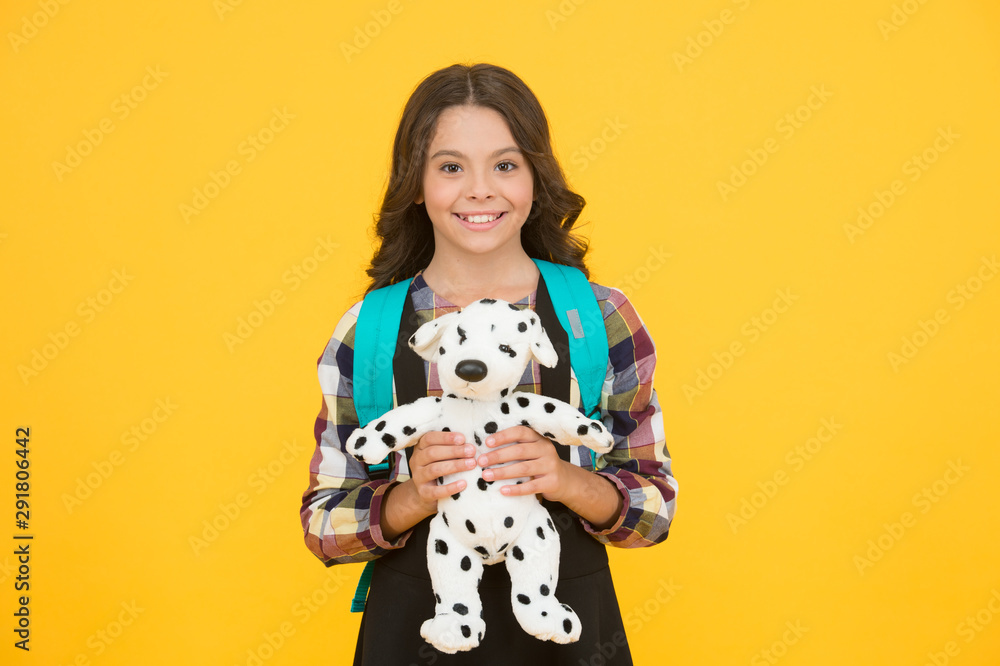 Little schoolgirl with toy and backpack. Happy childhood. Education concept. Beginning of academic year. Studying in primary school. Kindergarten and primary education. Education for small children Little schoolgirl with toy and backpack. Happy childhood. Education concept. Beginning of academic year. Studying in primary school. Kindergarten and primary education. Education for small children