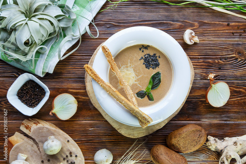 Mushroom soup with pasta with champignons and herbs on a brown wooden background