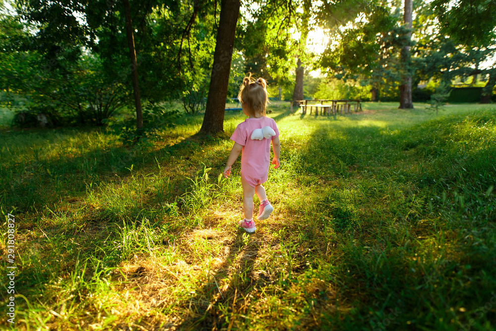little girl walking in the green garden in summer in sunny day. portrait of a little girl in pink dress in the green park in sunny day. cute baby on a walk outdoor.little angel girl. little girl walking in the green garden in summer in sunny day. portrait of a little girl in pink dress in the green park in sunny day. cute baby on a walk outdoor.little angel girl.