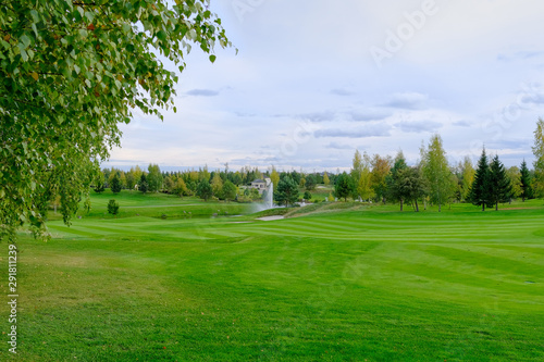 Landscape. Hills with green lawn and ornamental shrubs, trees, lake and fountain. It's a beautiful garden.