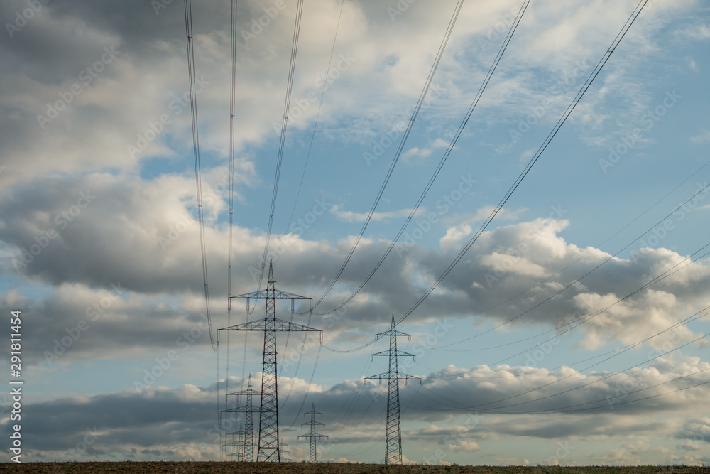 Strommasten unter dunklem Wolkenhimmel