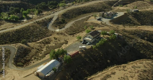 Aerial helicopter shot, zoom in on Santa Clarita ranch, solar panels on roof, circle around it, drone footage photo