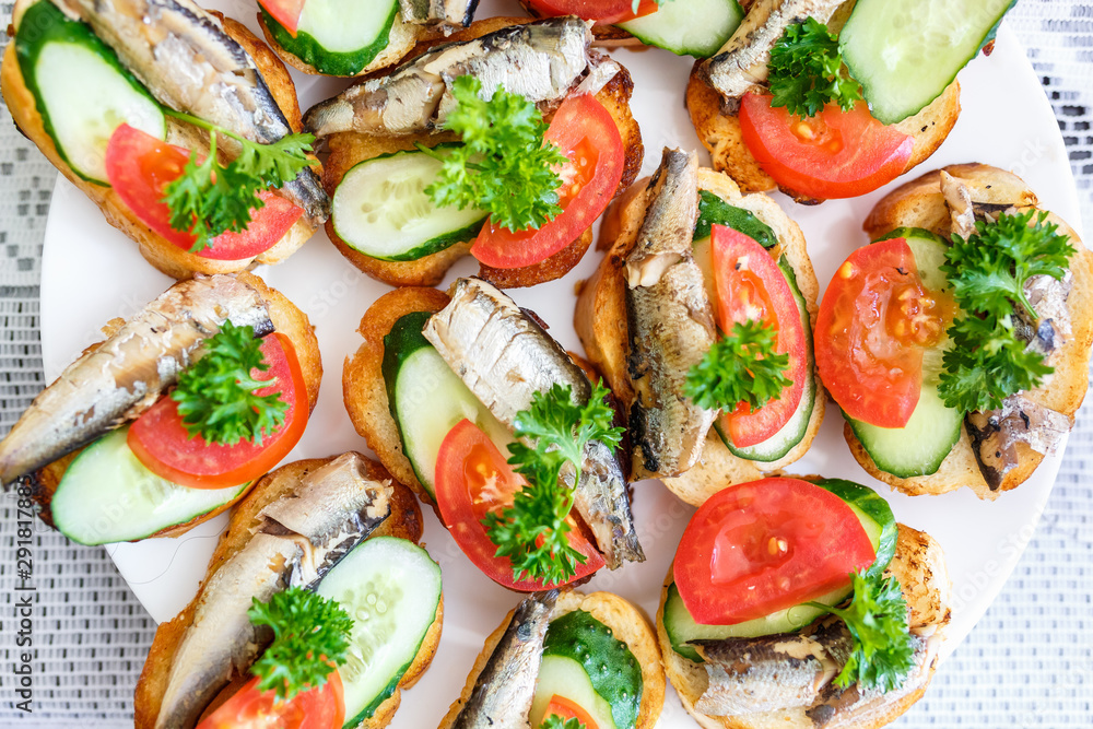 plate of sandwiches from long loaf, sprats, tomatoes, cucumbers and parsley plate of sandwiches from long loaf, sprats, tomatoes, cucumbers and parsley