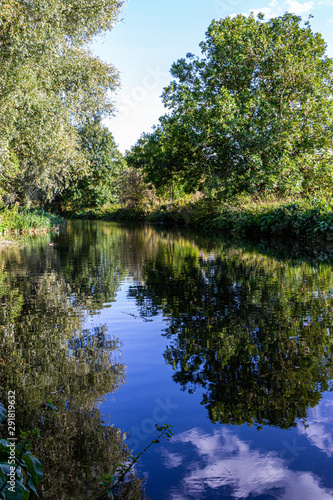 walkway beside the river with sky and trees reflected in it