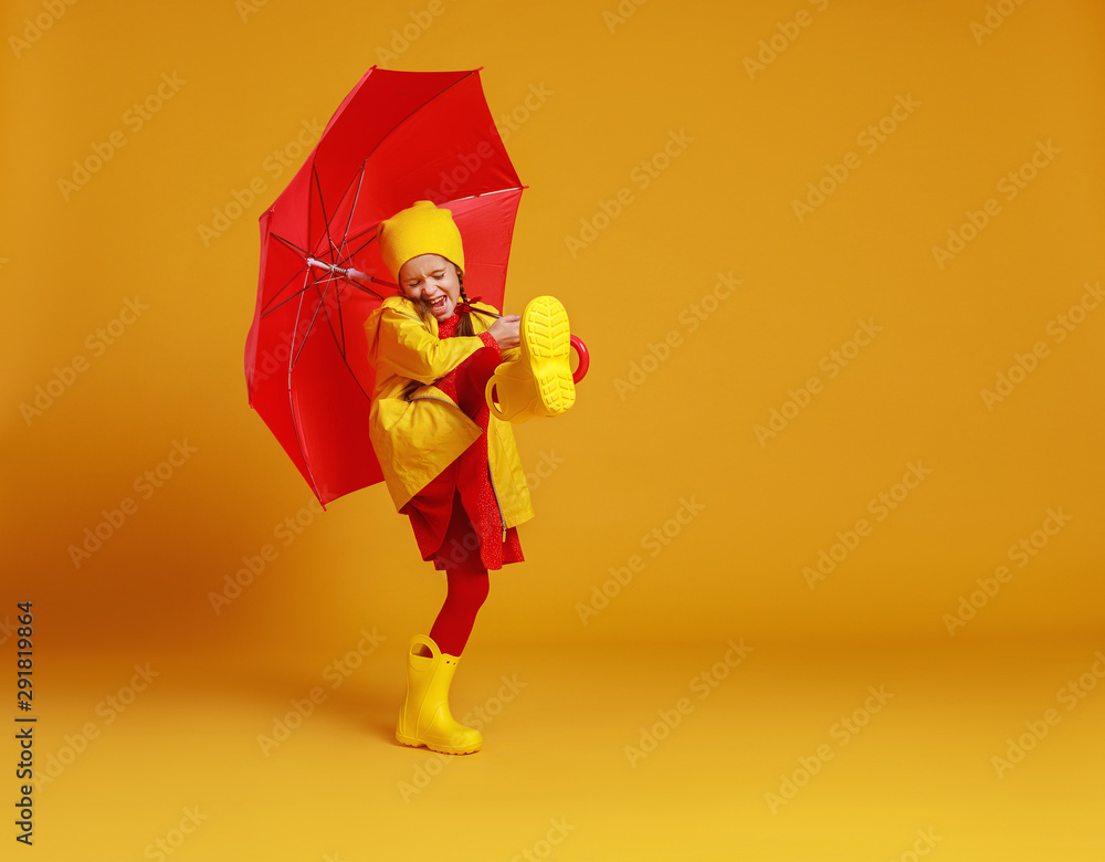 happy emotional cheerful child girl laughing  with red umbrella   on colored yellow background.