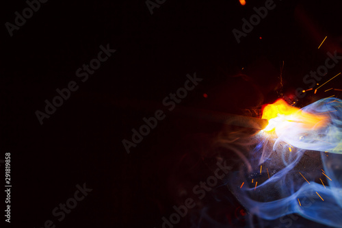 Arc welding. Welding of two sheets of metal by electrode in inert gases. Type MMA. A bright flash of light and a sheaf of sparks in a cloud of smoke. Miniature Universe. Free space for inscriptions.