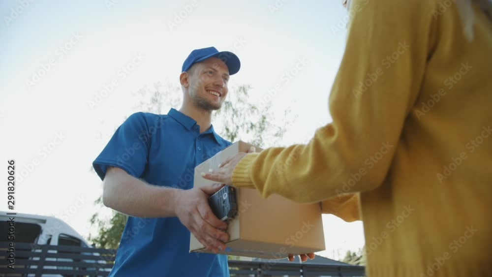 Beautiful Young Woman Meets Delivery Man who Gives Her Cardboard Box Package, She Signs Electronic Signature POD Device. Courier Delivering Parcel in the Suburban Neighborhood. Slow Motion Low Angle Beautiful Young Woman Meets Delivery Man who Gives Her Cardboard Box Package, She Signs Electronic Signature POD Device. Courier Delivering Parcel in the Suburban Neighborhood. Slow Motion Low Angle