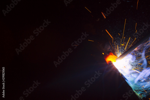 Arc welding. Welding of two sheets of metal by electrode in inert gases. Type MMA. A bright flash of light and a sheaf of sparks in a cloud of smoke. Miniature Universe. Free space for inscriptions.