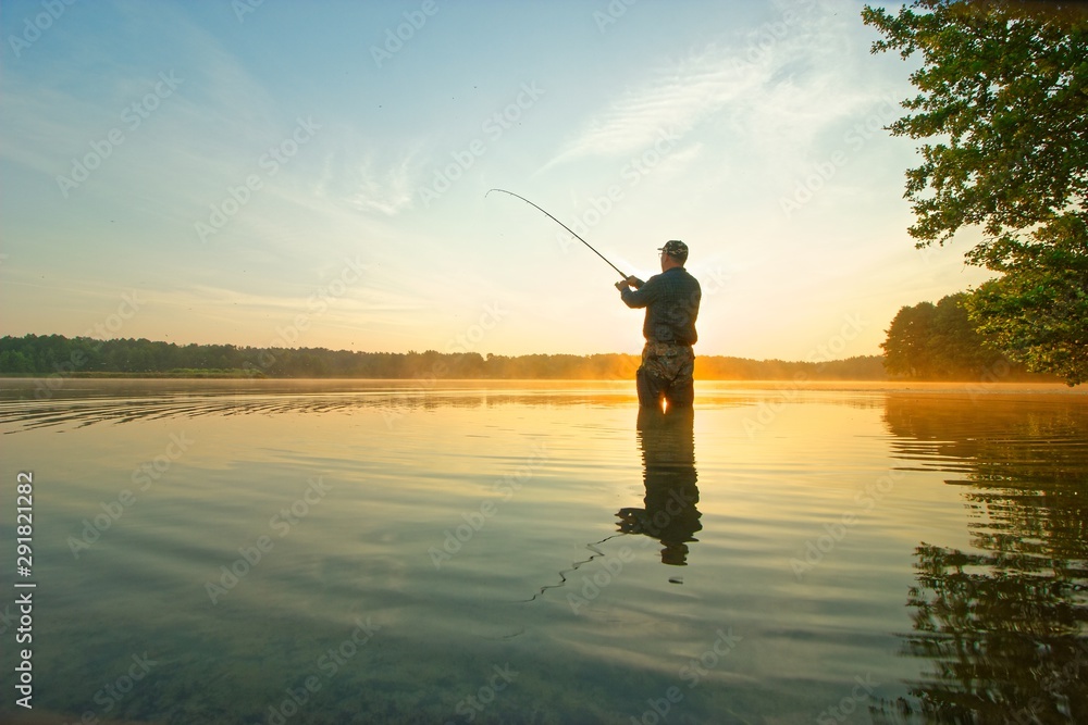 Angler standing in the lake during sunrise Angler standing in the lake during sunrise