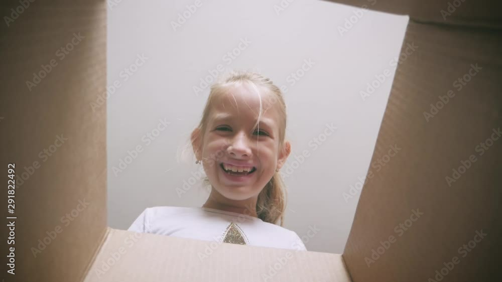 Surprised girl unpacking and opening carton box and looking inside. Child emotions concept. Surprised girl unpacking and opening carton box and looking inside. Child emotions concept.