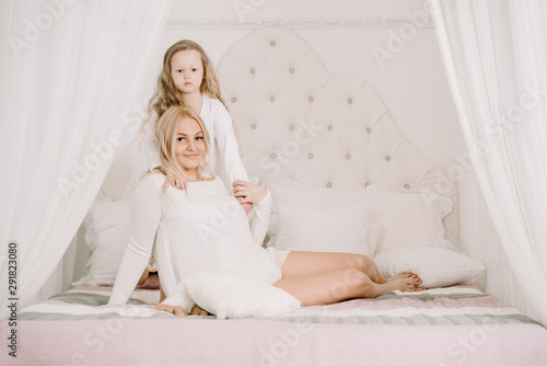 Portrait of a joyful mother and her daughter having relax and joy at the bed on white background © goldeneden