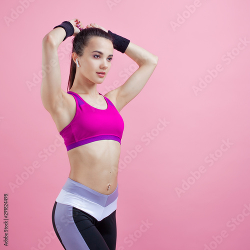 Young athletic attractive girl brunette with a ponytail in a bright tight top straightens her hair, high ponytail. © Ulia Koltyrina