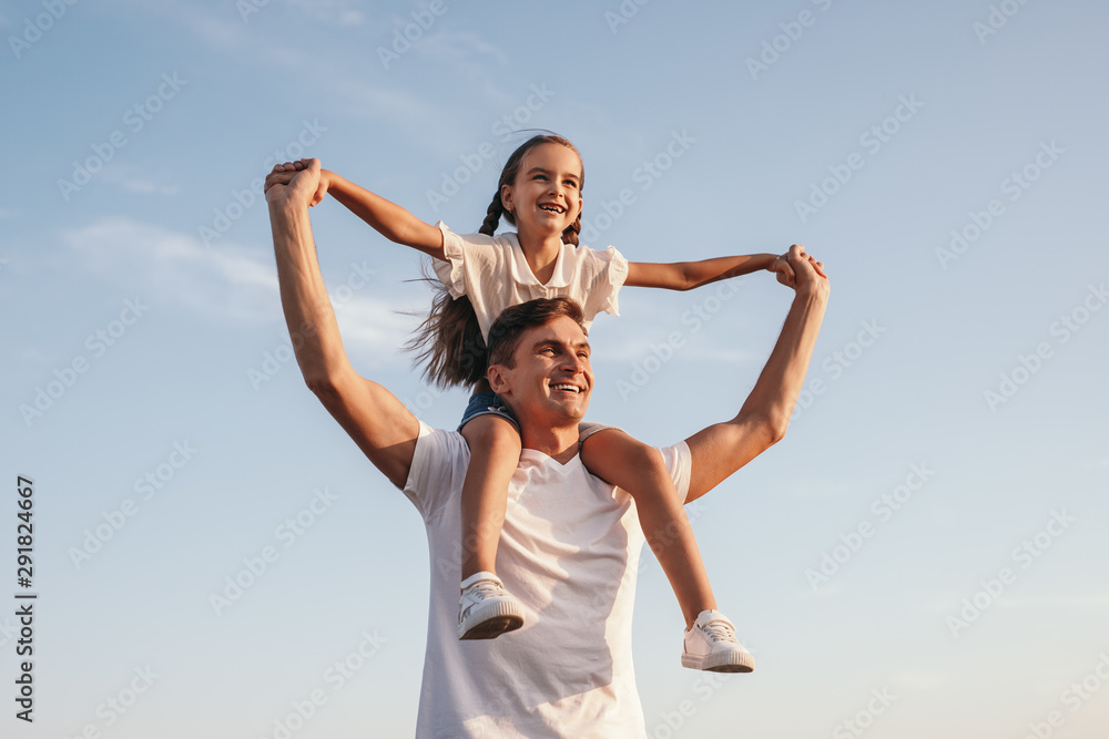 Joyful man with girl on shoulders raising hand together Joyful man with girl on shoulders raising hand together