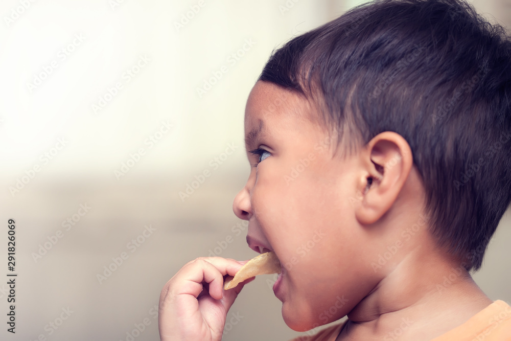 A kid forcibly putting a unhealthy potato chip snack in his mouth for eating while parents are away. A kid forcibly putting a unhealthy potato chip snack in his mouth for eating while parents are away.