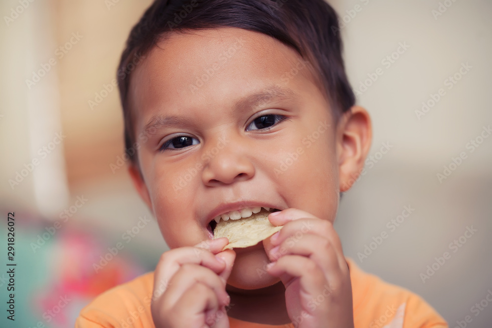 A cute young boy enjoying a unhealthy potato chip snack that he is holding to his mouth and is ready to bite. A cute young boy enjoying a unhealthy potato chip snack that he is holding to his mouth and is ready to bite.