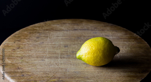 Fotografie Fresh lemons on wooden table with black background