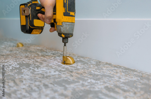 Builder in installing doorstop in a modern house, in using screwdriver photo