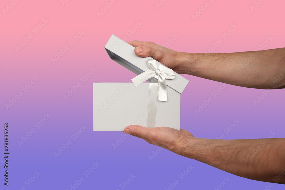 man holding a gift in a light gray box with a satin ribbon and a bow, the concept of Valentine's Day, Christmas presents, mother's day, new year, close-up, copy space man holding a gift in a light gray box with a satin ribbon and a bow, the concept of Valentine's Day, Christmas presents, mother's day, new year, close-up, copy space