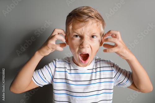 Foto Portrait of angry little boy on grey background