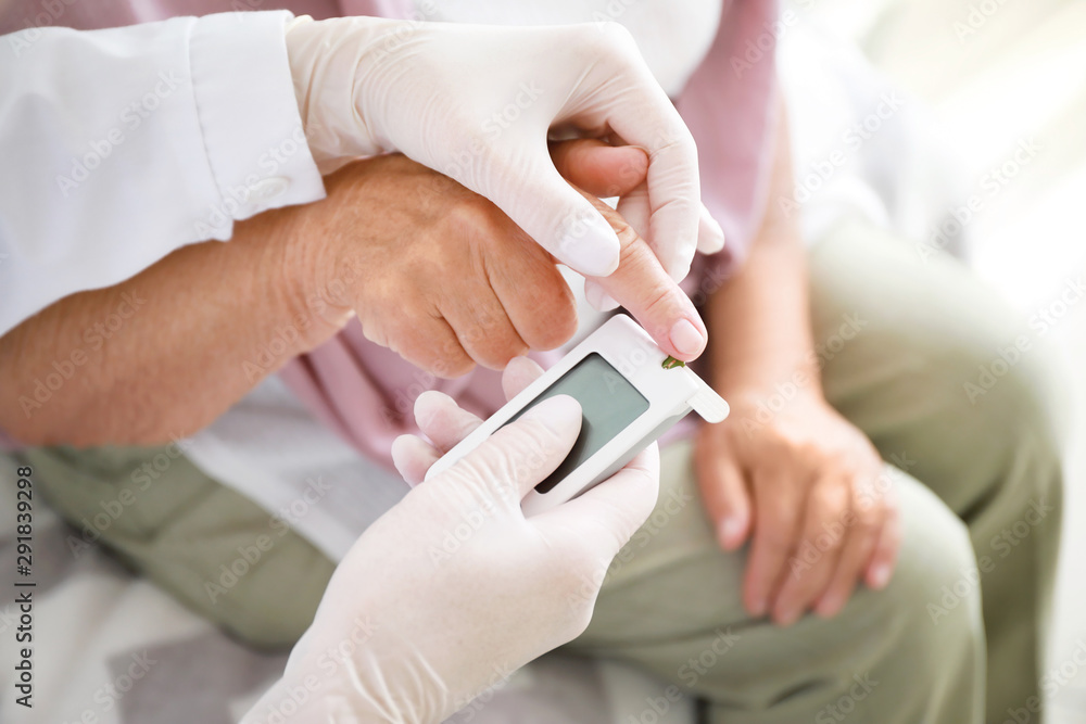Doctor checking blood sugar level of diabetic woman at home, closeup