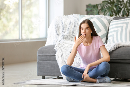 Shocked young girl sitting on floor at home