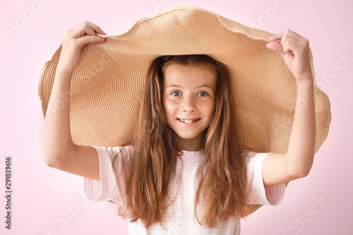 Stylish little girl in big hat on color background