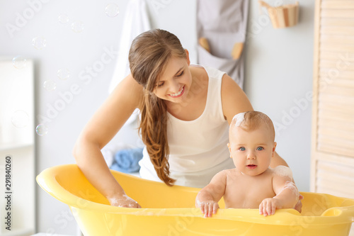 Mother bathing her cute lit...