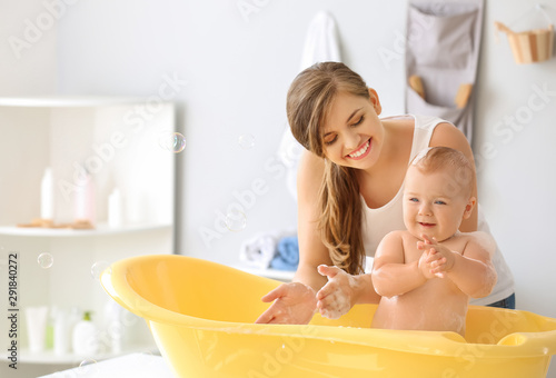 Mother bathing her cute lit...