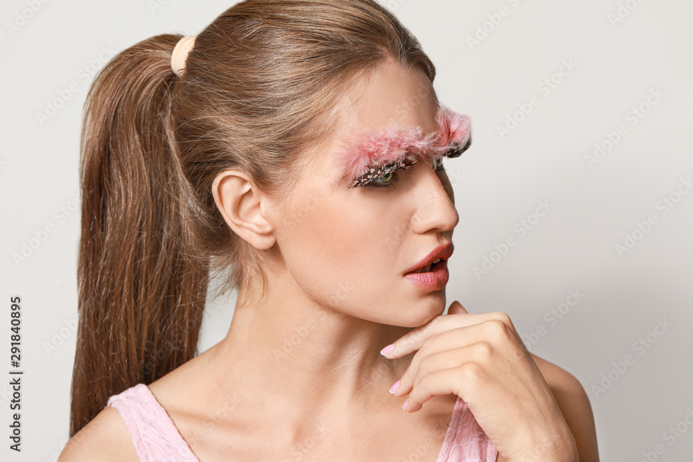 Fototapeta premium Young woman with creative eyelashes and eyebrows on grey background