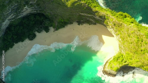 Happy couple enjoy honeymoon vacation on Kelingking Beach on background amazing nature landscape. 4K Aerial view with smooth distance from the people. Inodnesia, Nusa Penida photo