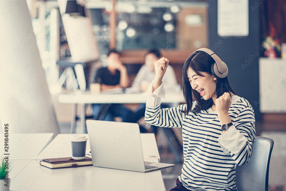 Fototapeta premium Cheerful young Asian girl celebrate after finish her work. Successful concept for small business start up, university education, new entrepreneur or freelancer.