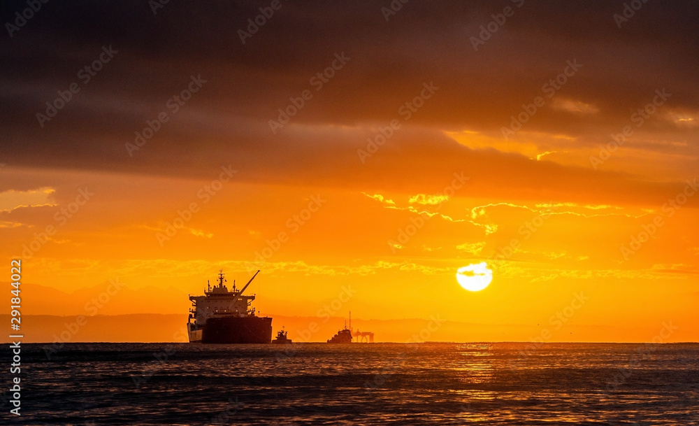 Oil tankers ship at sea on a background of sunset sky. Oil tankers in the ocean. Early in the morning, the sunrise sky. South Africa. Mossel Bay Oil tankers ship at sea on a background of sunset sky. Oil tankers in the ocean. Early in the morning, the sunrise sky. South Africa. Mossel Bay