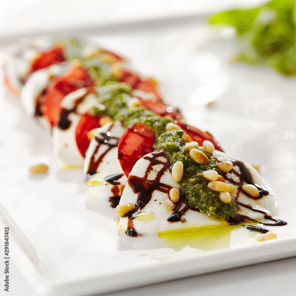 Gourmet, restaurant, delicious dinner food - close up of Caprese Salad. Salad with Tomatoes, Mozzarella Cheese, Balsamic. Salad Dressing with Pesto Sauce and Rocket Salad Gourmet, restaurant, delicious dinner food - close up of Caprese Salad. Salad with Tomatoes, Mozzarella Cheese, Balsamic. Salad Dressing with Pesto Sauce and Rocket Salad