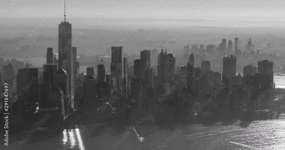 Black and white aerial shot, east-facing examination of financial district, end pan focus on One World Trade Center, drone