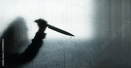 Murderer or robber with big knife in hand behind Frosted glass in the bathroom background,concept of scary crime scene of horror or thriller movies,Halloween theme,Silhouette style