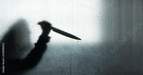 Tableau sur toile Murderer or robber with big knife in hand behind Frosted glass in the bathroom b