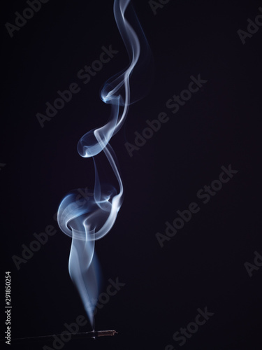 White smoke swirling on black background, close up view, isolated. Structure of white smoke, brush effect. Eastern burning incense for meditation and relaxation, abstract background