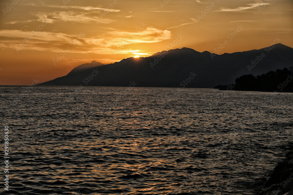 Sunset over the mountains by the wavy sea
