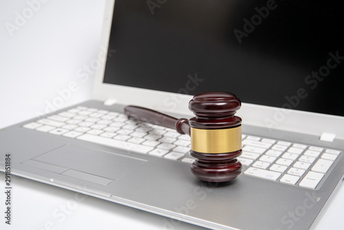 Wooden judge gavel on a silver laptop computer, cyber law or online auction concept.