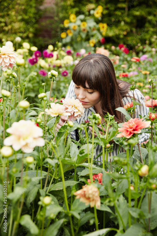 Woman smelling flowers in a garden on a farm Woman smelling flowers in a garden on a farm