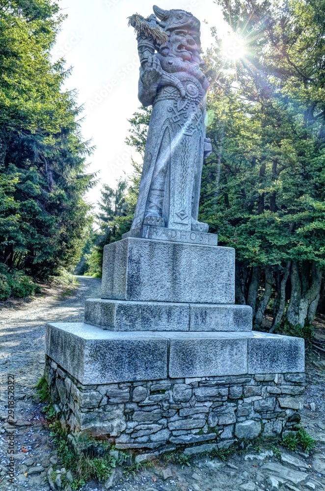 Radegast God stone statue on pedestal against sun