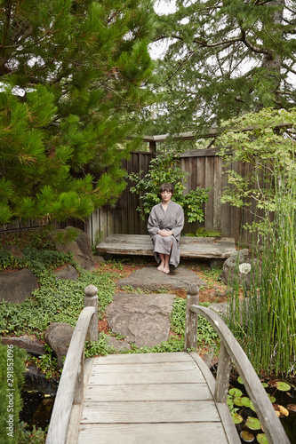 Woman sitting and meditating in Japanese garden photo