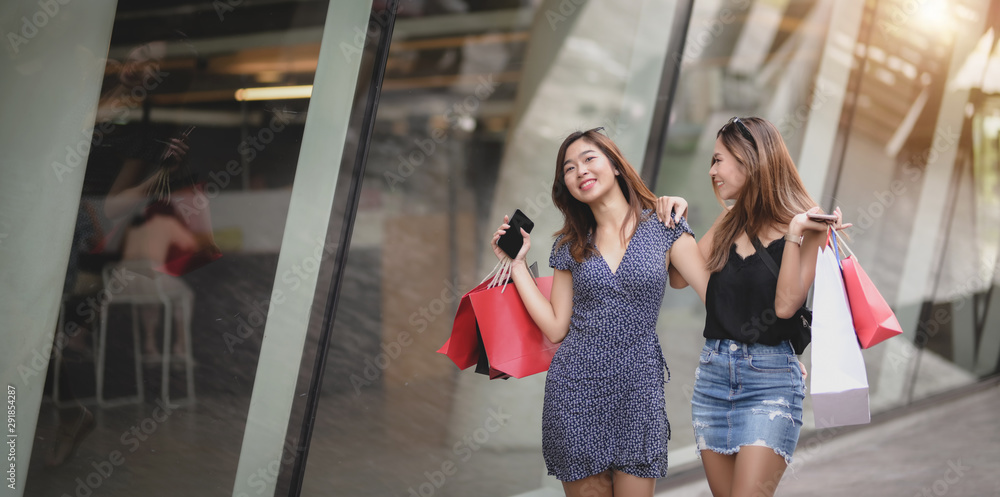 Two beautiful asian women talking together while spending their time shopping