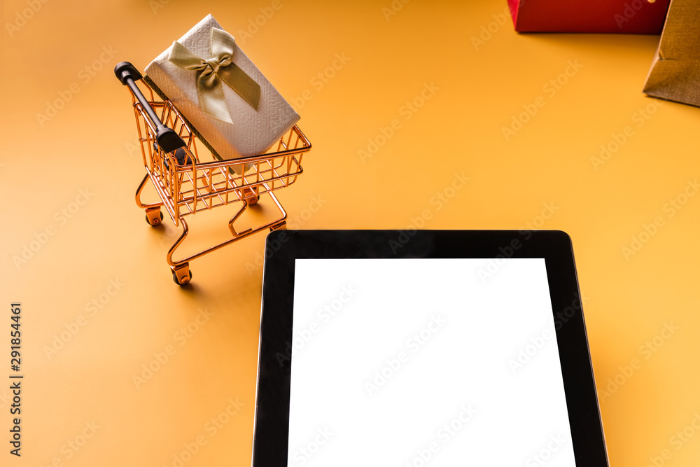 Shopping cart model and tablet on yellow background