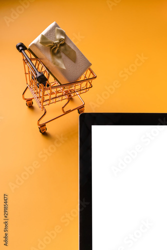Shopping cart model and tablet on yellow background
