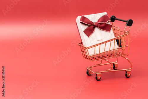 Shopping cart model with a gift box on a red background © 春华 王