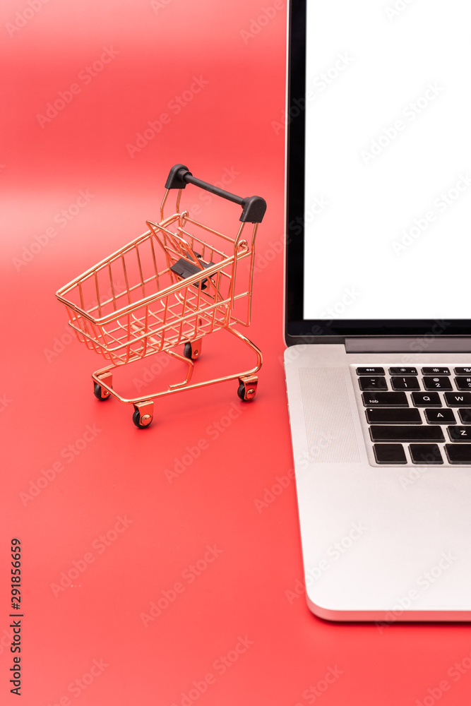 Laptop and shopping cart model on red background