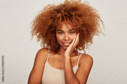 beautiful African American woman looking at camera touching face photo